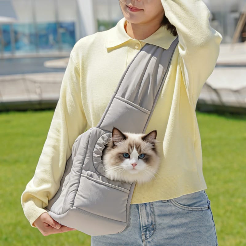 Light gray cat carrier purse worn crossbody with a cat inside